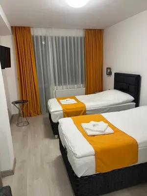 a hotel room with two beds with orange curtains at Хотел Лилия in Rudozem