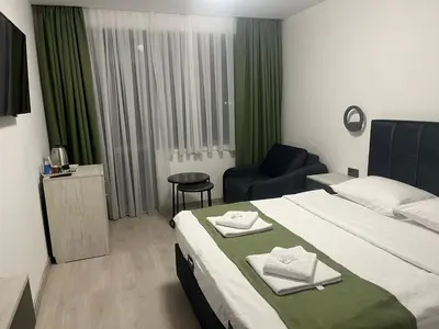 a hotel room with a bed and a chair at Хотел Лилия in Rudozem