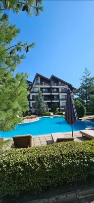 a pool with an umbrella and chairs and a building at Aspen Suites Luxury apartment A005 in Razlog