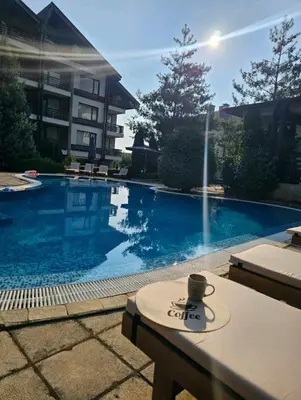 a swimming pool with a cup of coffee on a table at Aspen Suites Luxury apartment A005 in Razlog