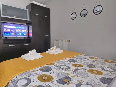 a bedroom with a bed with a yellow blanket and a tv at Mladost Sofia, close to Metro Station and Center in Sofia