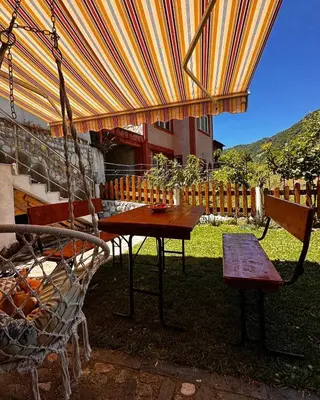 a table and chairs under an umbrella in a yard at Къща за гости Димитрови guest house Dimitrovi in Devin