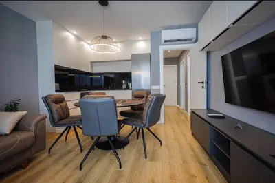 a living room with a table and chairs and a television at Gran Capital - Vodolei Garden, FREE Parking in Sofia