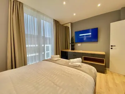 a bedroom with a large bed and a tv at Gran Capital - Vodolei Garden, FREE Parking in Sofia