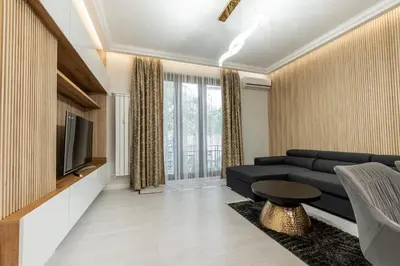 a living room with a black couch and a tv at Vitoshka Luxury 2-BR Retreat in Sofia