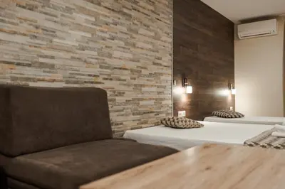 a bedroom with two beds and a chair and a brick wall at Dias in Sandanski