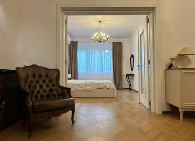 a bedroom with a bed and a chair and a chandelier at Apartament 86 in Sofia