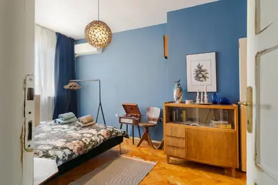a bedroom with a bed and a blue wall at ART-ament, a unique central flat in Sofia