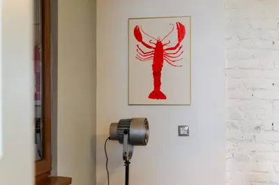 a red lobster picture on a white wall with a floor lamp at ART-ament, a unique central flat in Sofia