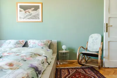 a bedroom with a bed and a chair at ART-ament, a unique central flat in Sofia
