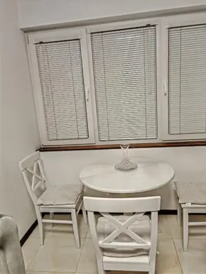 a white table and chairs in a room with windows at Apartament 88 in Sofia