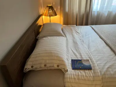 a bed in a bedroom with a lamp and a book at Laurel & Hardy - Old city center Apart in Sofia