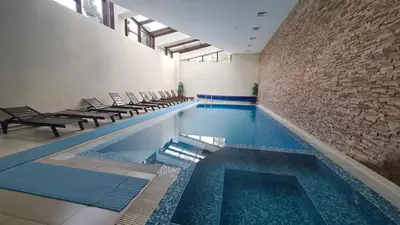 a swimming pool with chairs and a brick wall at Aspen Golf Resort and SPA, Studio J006 in Bansko