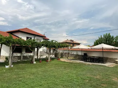 a house with a yard with tables and umbrellas at Къща за гости Бадови in Hisarya