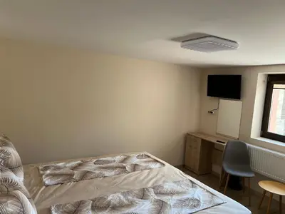 a bedroom with a bed and a desk and a tv at Къща за гости Бадови in Hisarya