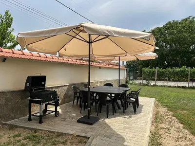 a table and chairs under an umbrella on a patio at Къща за гости Бадови in Hisarya