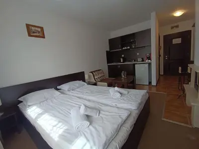 a bedroom with a large white bed with towels on it at Студио в хотел Мария Антоанета in Bansko