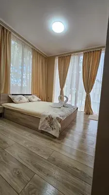a bedroom with a large bed in front of windows at Апартаменти за гости Кедър in Sapareva Banya
