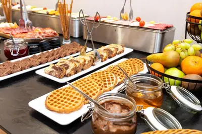 a buffet with plates of food and waffles and fruit at AMAR Design Hotel by HMG in Sofia