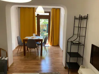 a dining room with a table and chairs and yellow curtains at Garden apartment in Karlovo