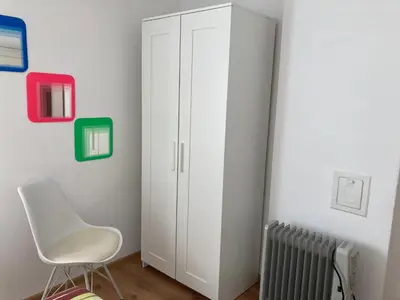 a white cabinet in a room with a chair at Garden apartment in Karlovo