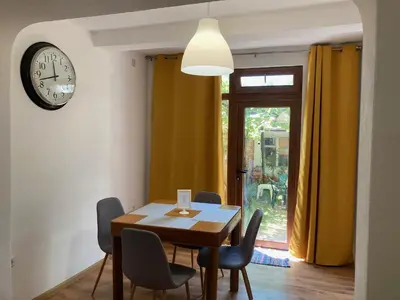 a dining room with a table and chairs and a clock at Garden apartment in Karlovo