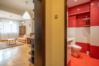 a bathroom with a toilet and a living room at Pirotska 2-Bedroom 100m2 Apartment in Sofia Center in Sofia
