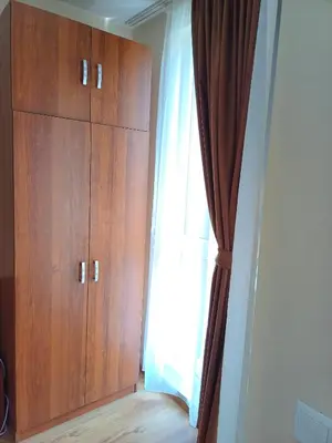a bedroom with a wooden cabinet and a window at Апартамент - Студио Престиж 3 in Hisarya