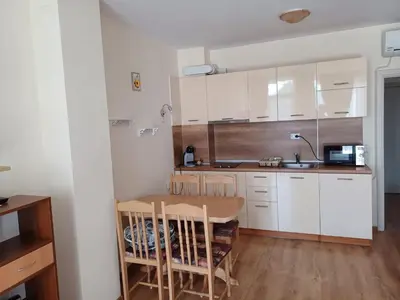 a kitchen with white cabinets and a wooden table at Апартамент - Студио Престиж 3 in Hisarya