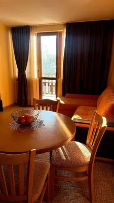 a living room with a table and chairs and a couch at Апартаменти Хармония in Pamporovo