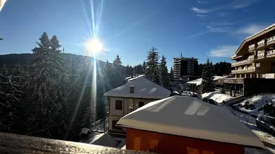 a view of a snowy mountain with the sun in the sky at Апартаменти Хармония in Pamporovo