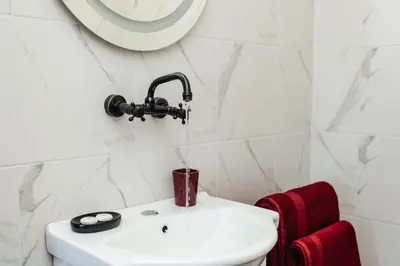 a white bathroom with a sink and a mirror at Къщи БРИК вила 2 in Sapareva Banya