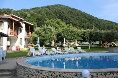 a person sitting in chairs next to a swimming pool at By the River Hotel Complex in Balkanets
