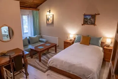 a bedroom with a bed and a couch and a table at Костовският хан in Chepelare