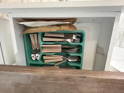 a green container filled with knives and other kitchen utensils at Smile House in Plovdiv