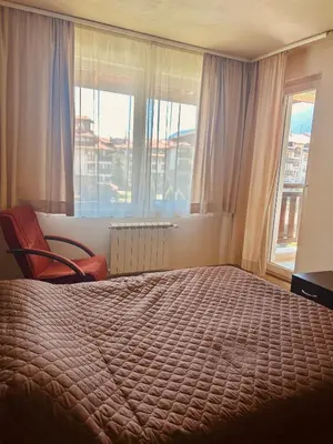 a bedroom with a bed and a chair and windows at View Apartment Bansko Royal Towers in Bansko