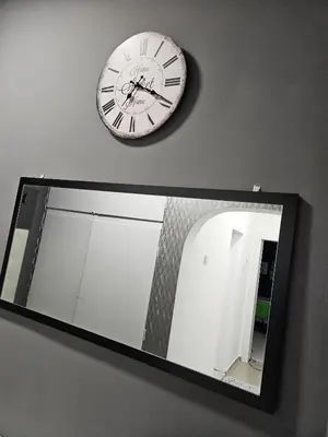 a clock hanging on a wall above a mirror at Апартамент Лилия in Gotse Delchev