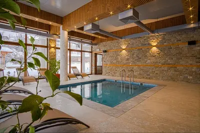 a swimming pool in a room with a brick wall at SPA Apartament Daffi in Smolyan