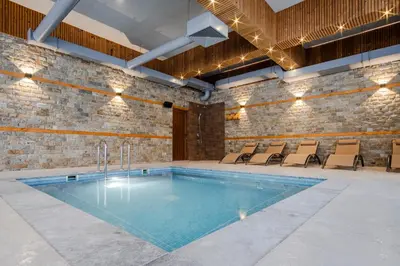 a swimming pool in a room with chairs around it at SPA Apartament Daffi in Smolyan