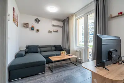 a living room with a couch and a tv at Cardinal Suite in Sofia