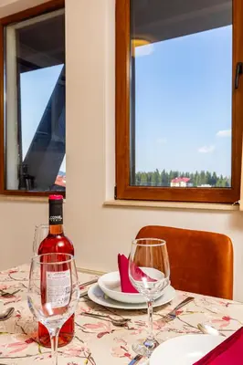 a bottle of wine sitting on a table with two glasses at Yanevi Apartments at Grand Monastery Pamporovo in Pamporovo