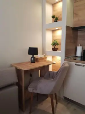 a kitchen with a wooden table with a chair and a lamp at Бутиково студио Joy-free parking in Plovdiv