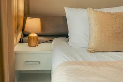 a bed with a nightstand with a lamp on it at Бутиково студио Joy-free parking in Plovdiv