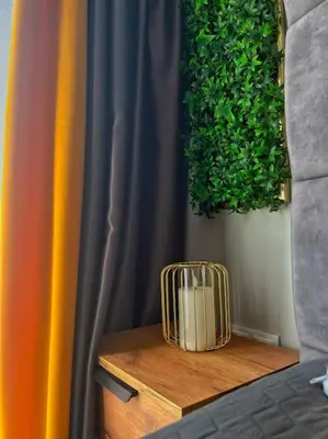 a vase on a wooden table next to a curtain at Бутиково студио Utopia in Plovdiv