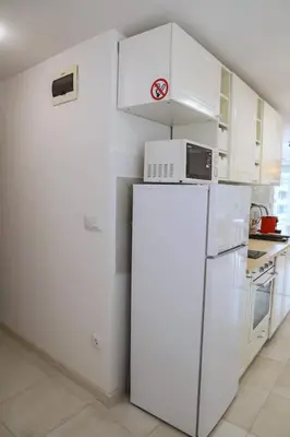 a white kitchen with a refrigerator and a microwave at Sophie Studio - Top center, Cozy & Work-Friendly near AUBG, Free streaming platforms in Blagoevgrad