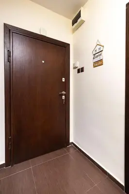 a wooden door in a hallway with a sign on the wall at Quiet Apartment in Plovdiv Ricky Home in Plovdiv