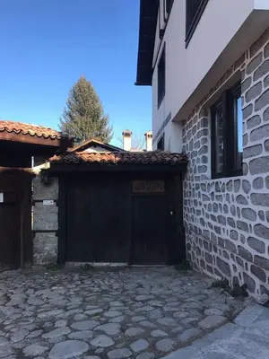 a garage with a wooden door next to a building at Matsureva House - Pri Ivan in Bansko