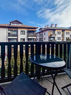a table and chairs on a balcony with buildings at Cosy Apartment On The Lift in Bansko
