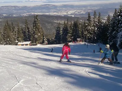 a group of people skiing down a snow covered slope at Zodiac House in Samokov