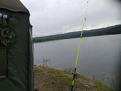 a tent with a fishing pole next to a lake at Zodiac House in Samokov